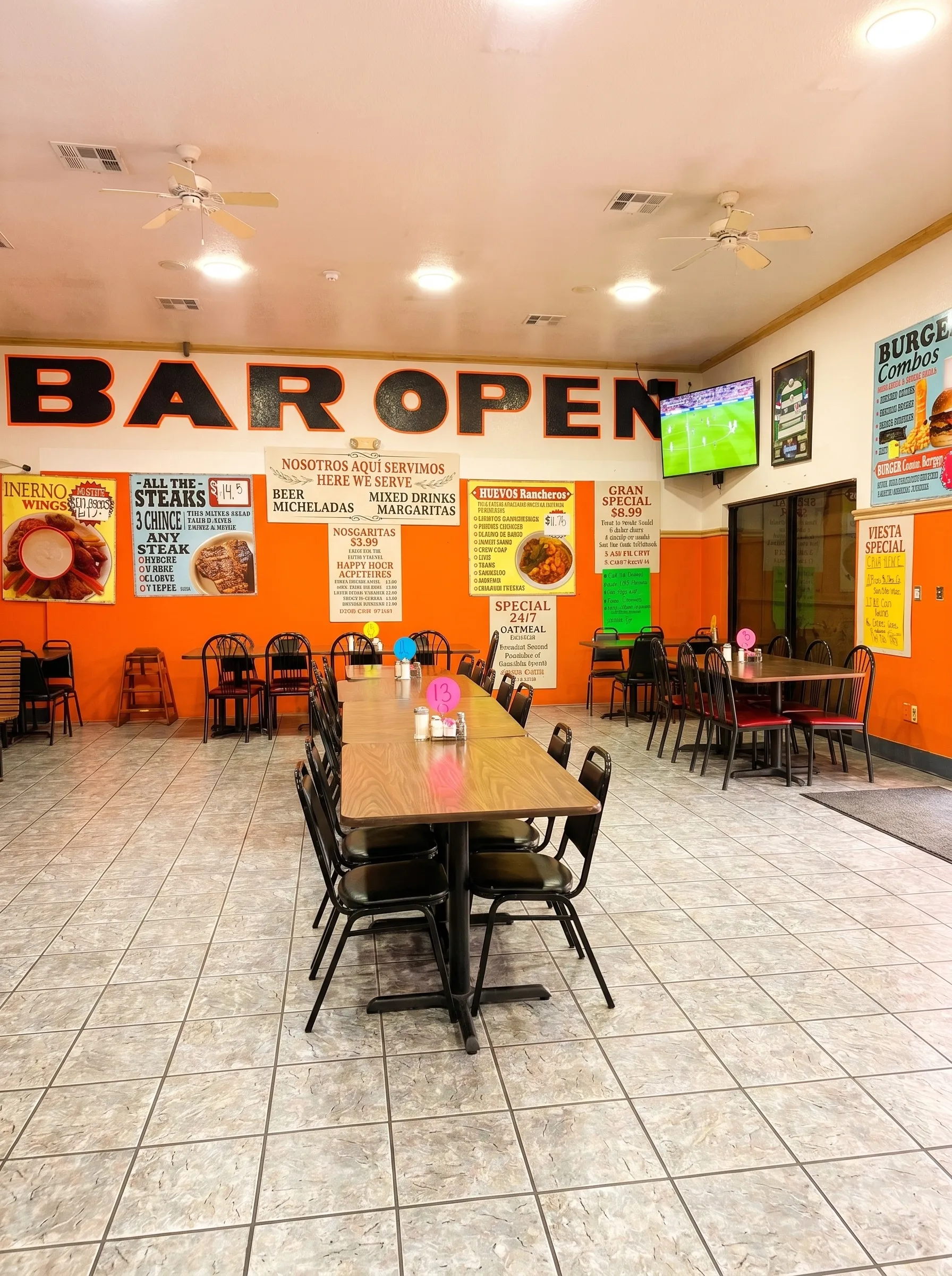 El Torreón interior with orange "Bar Open" mural wall, specials posters, and soccer on TV