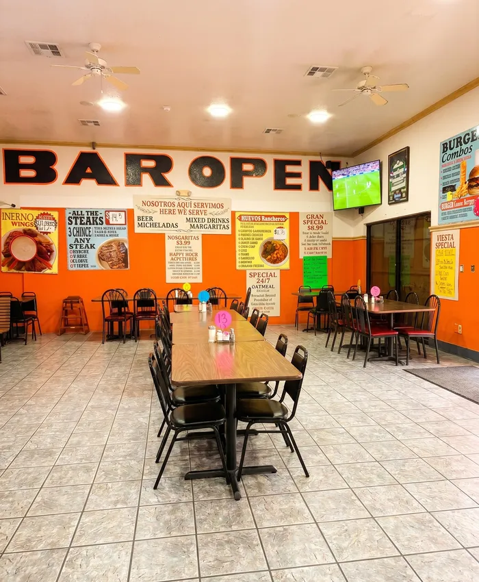 El Torreón interior bar area — orange BAR OPEN mural, specials posters, soccer on TV, busy atmosphere