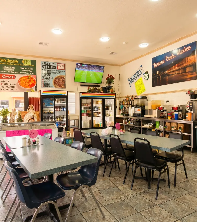 El Torreón interior showing the 'Torreón Coah. México' tower mural, steaks menu poster, drink coolers, and soccer on TV